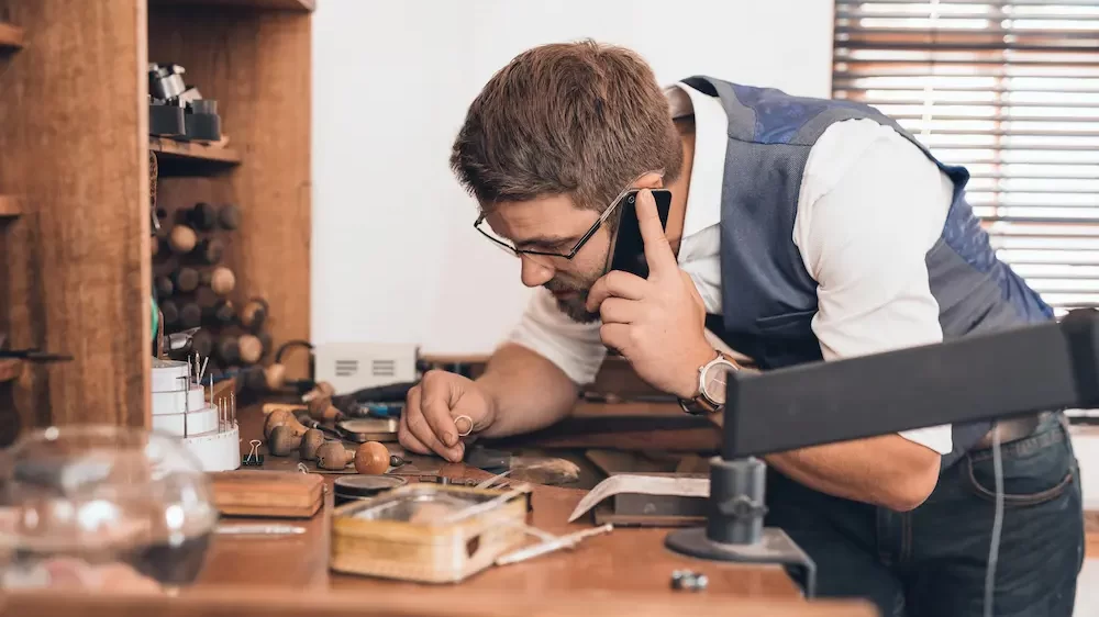 Jeweler examining ring and talking on cellphone