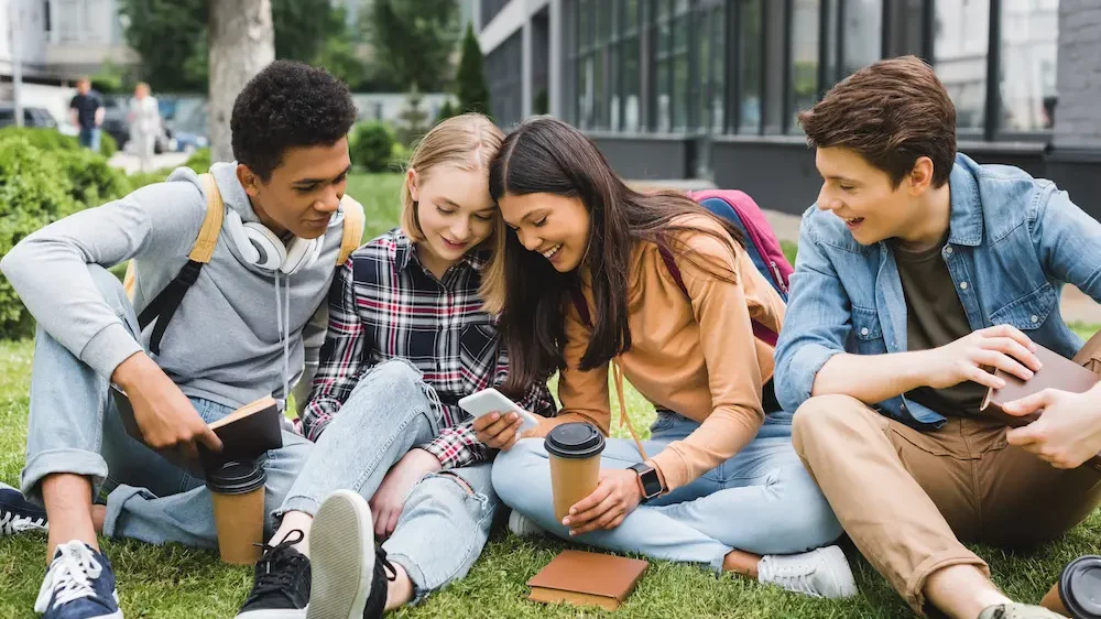 Smiling and happy teenagers sitting on grass