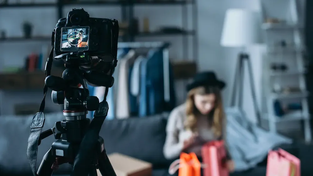 Fashion blogger sitting with shopping bags whilst recording a video