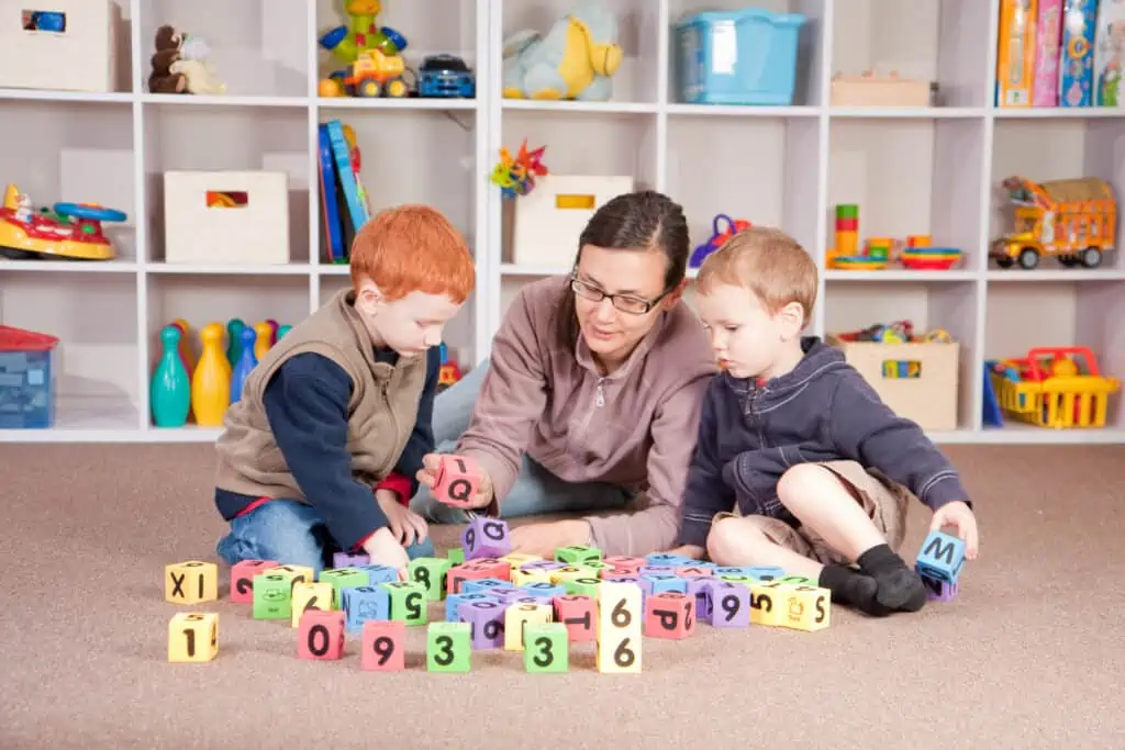 Boys playing game with kids blocks with mother