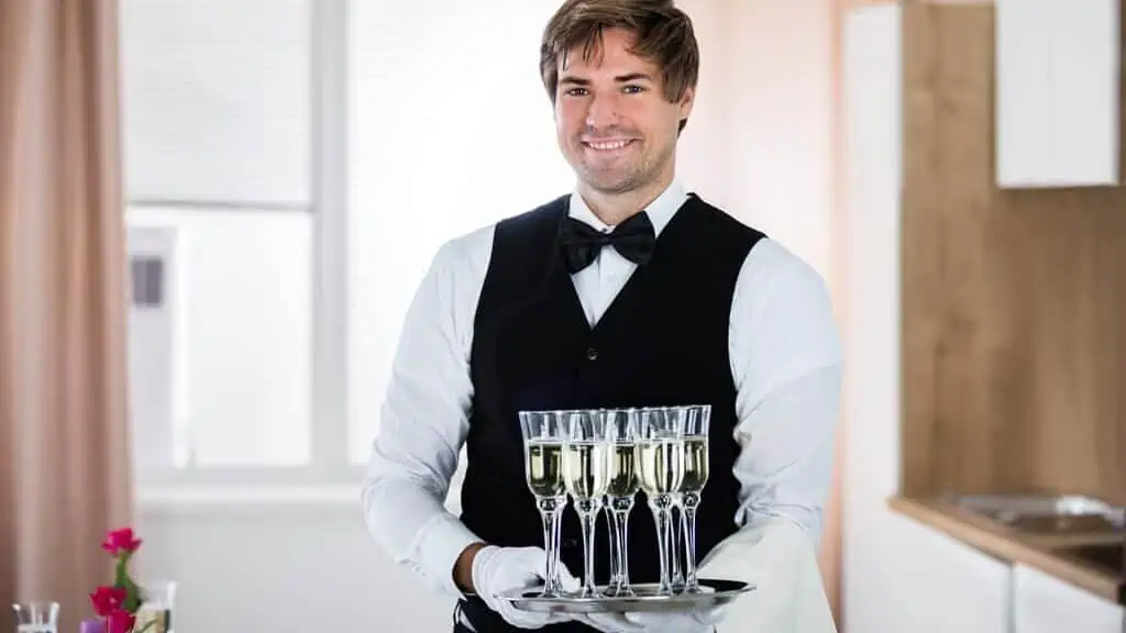 Smiling Waiter Holding Tray Of Champagne