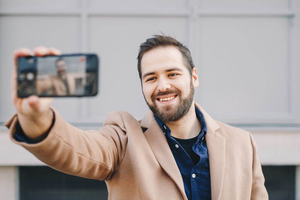 Close-up portrait of attractive and modern young man taking a selfie