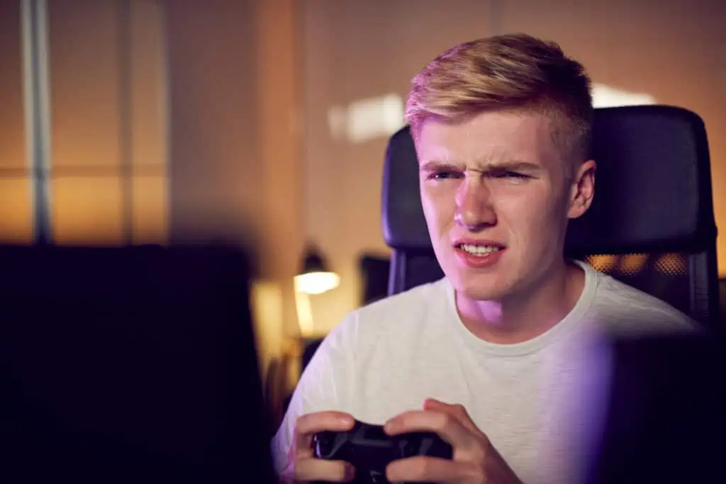 Teenage Boy With Game Pad Sitting In Chair and Gaming At Home