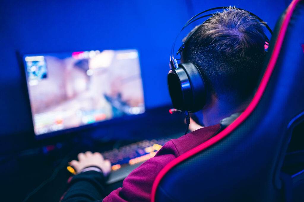 Professional gamer playing online games tournaments pc computer with headphones, Blurred red and blue background