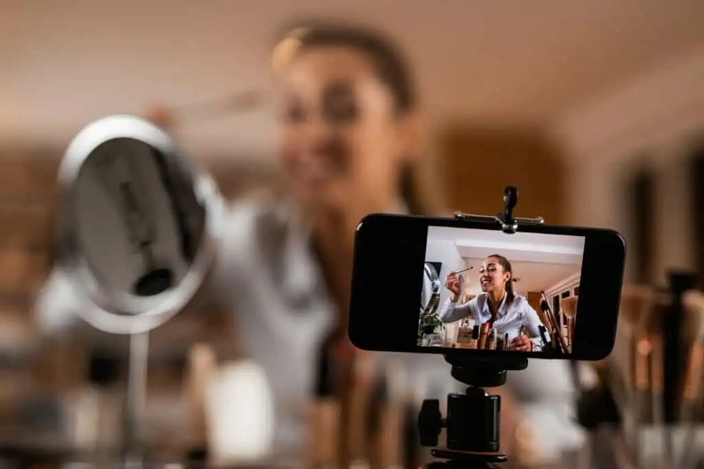 Close-up of female vlogger recording make-up tutorial at home.