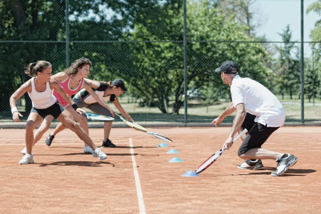 Instructor working with group of girls, touching markers on cardio tennis training