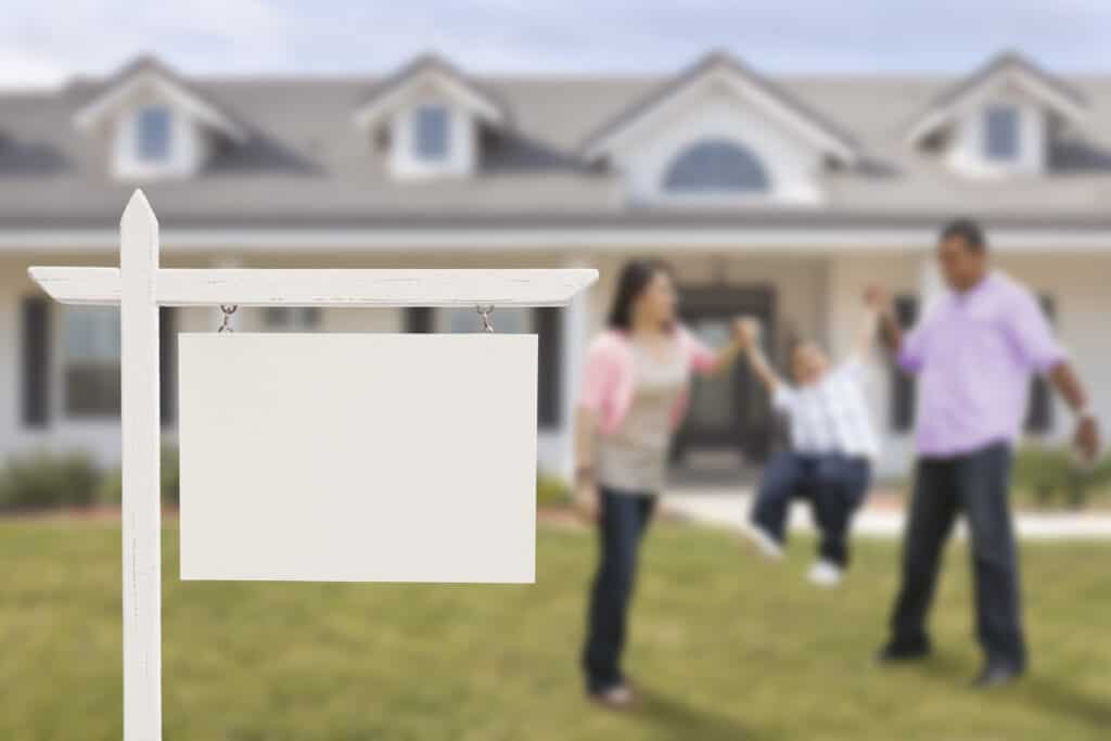 Blank Real Estate Sign and Playful Hispanic Family in Front of House.