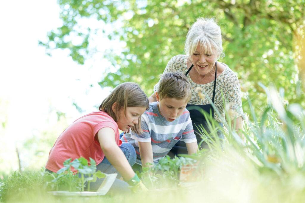 Elderly woman having fun gardening with grandkids