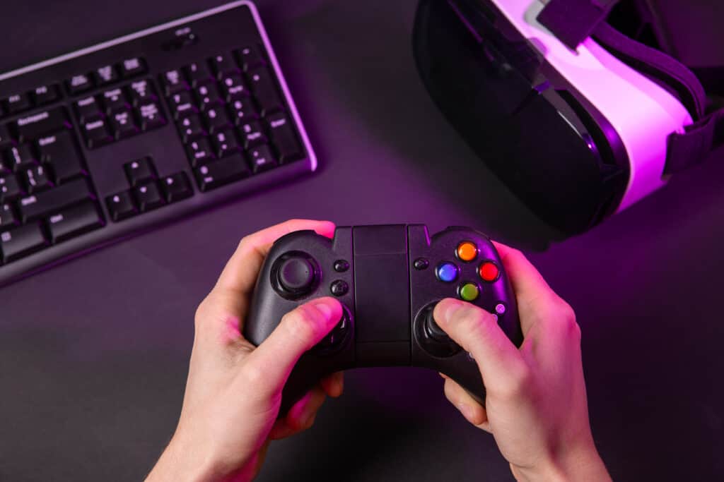 Man hands playing a computer game with a game joystick. Gamer workspace concept.