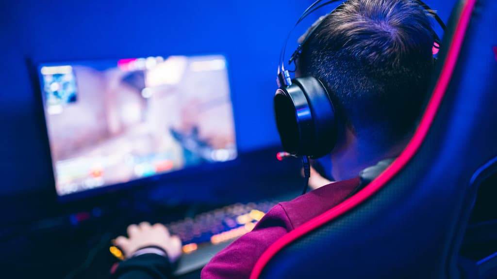 Professional gamer playing online games tournaments pc computer with headphones, Blurred red and blue background