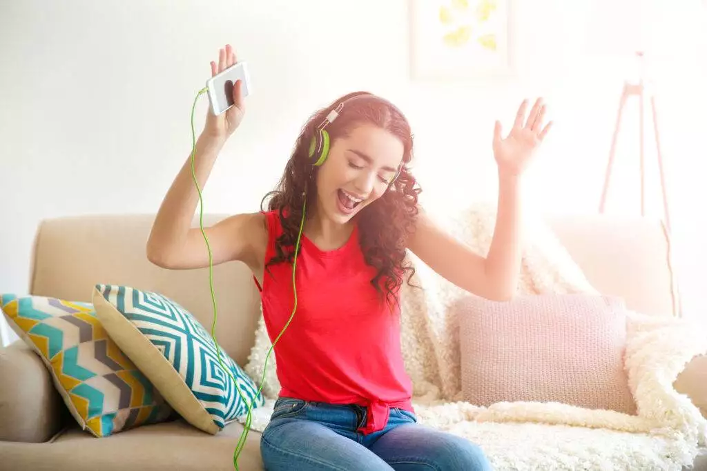 Beautiful young woman in headphones listening to music at home