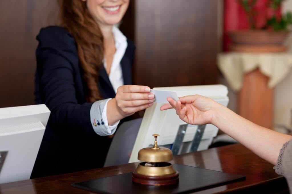 smiling female receptionist passing card to guest