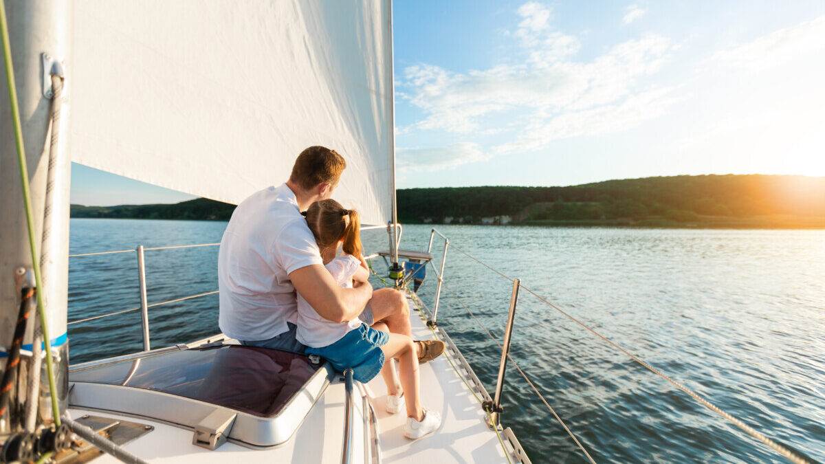 A couple sitting on a sailboat at sunset.