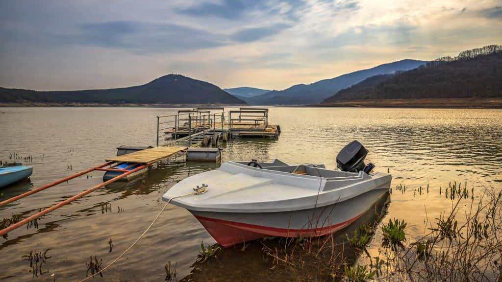 Moored wooden boat after sunset at the lakeshore