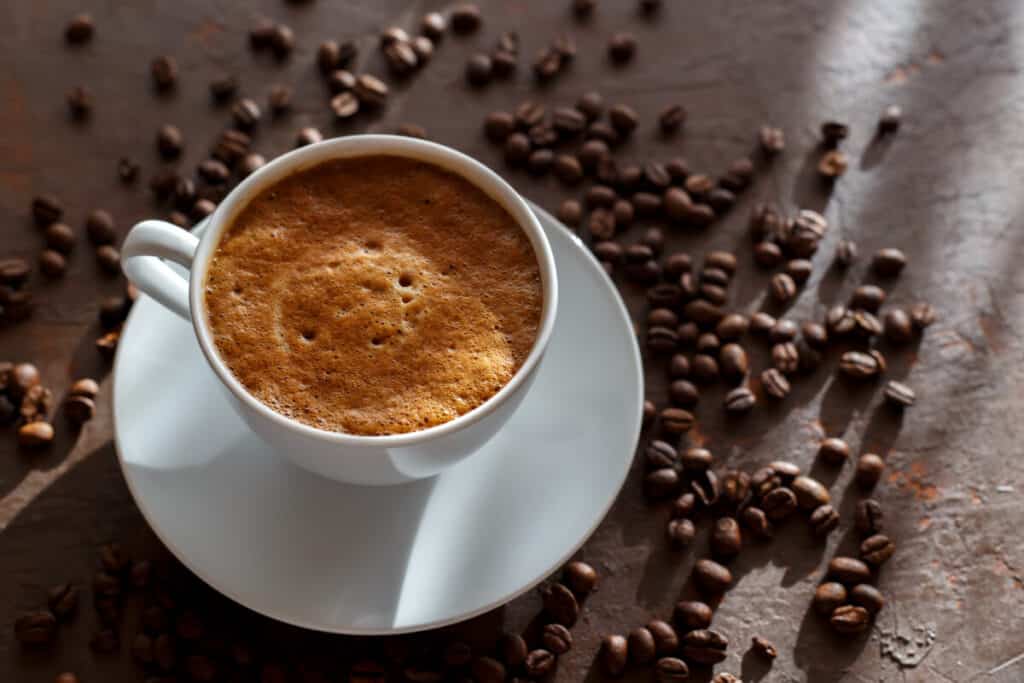 Cup of coffee cappuccino and coffee beans on the brown stone background