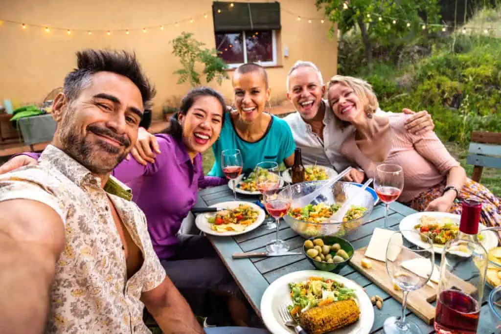 Happy group of friends laughing taking selfie during barbecue dinner party outdoors. Lifestyle.