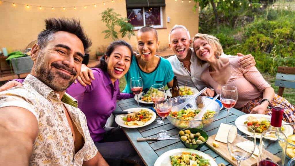 Happy group of friends laughing taking selfie during barbecue dinner party outdoors. Lifestyle.