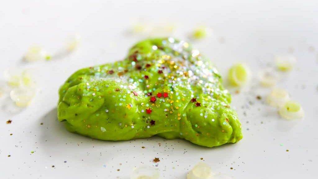 Green heart with shiny glitters made from slime by child