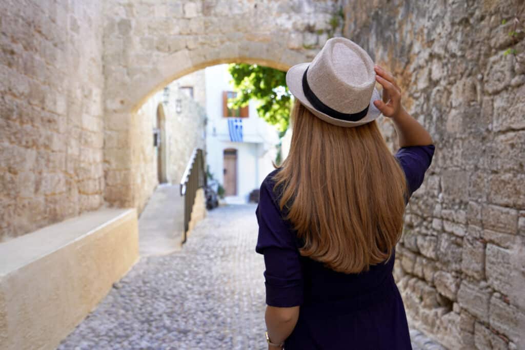 Travel in Greece. Back view of tourist girl visiting the old town of Rhodes, Greece.