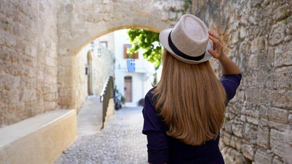 Travel in Greece. Back view of tourist girl visiting the old town of Rhodes, Greece.