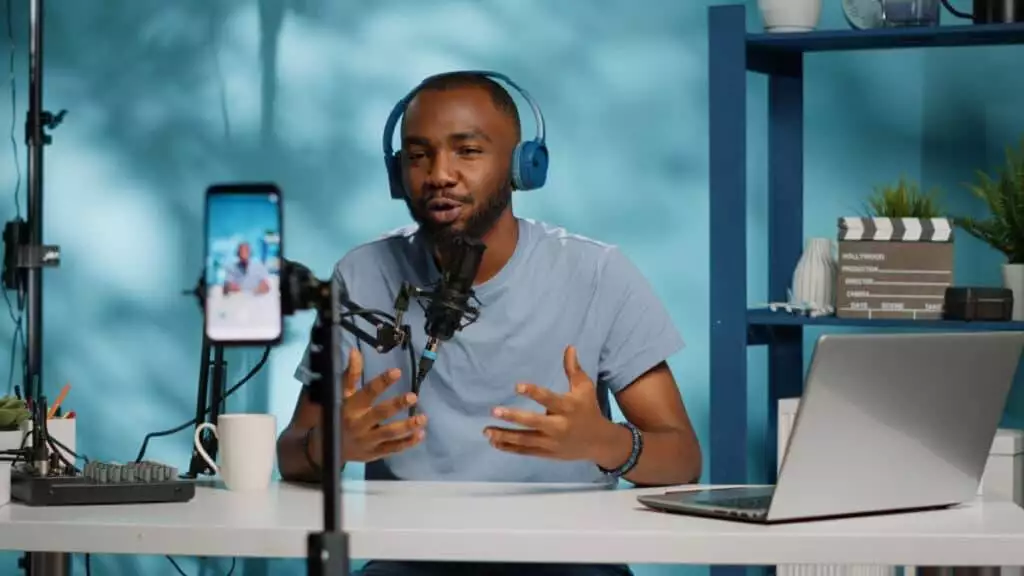 A man is sitting at a desk with headphones and a laptop.