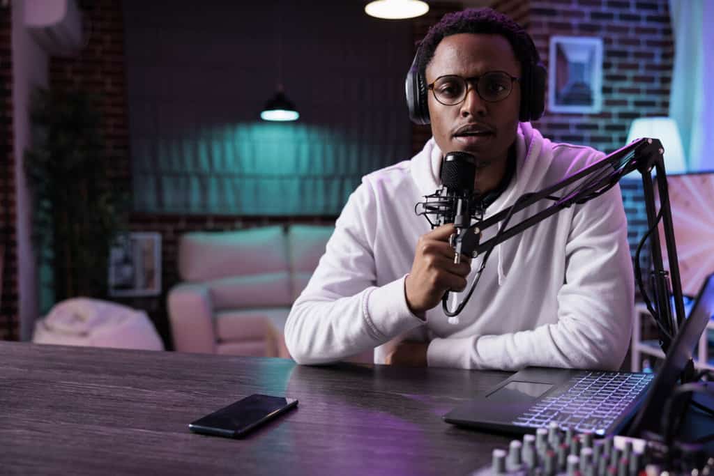 A man sitting at a desk in front of a microphone.
