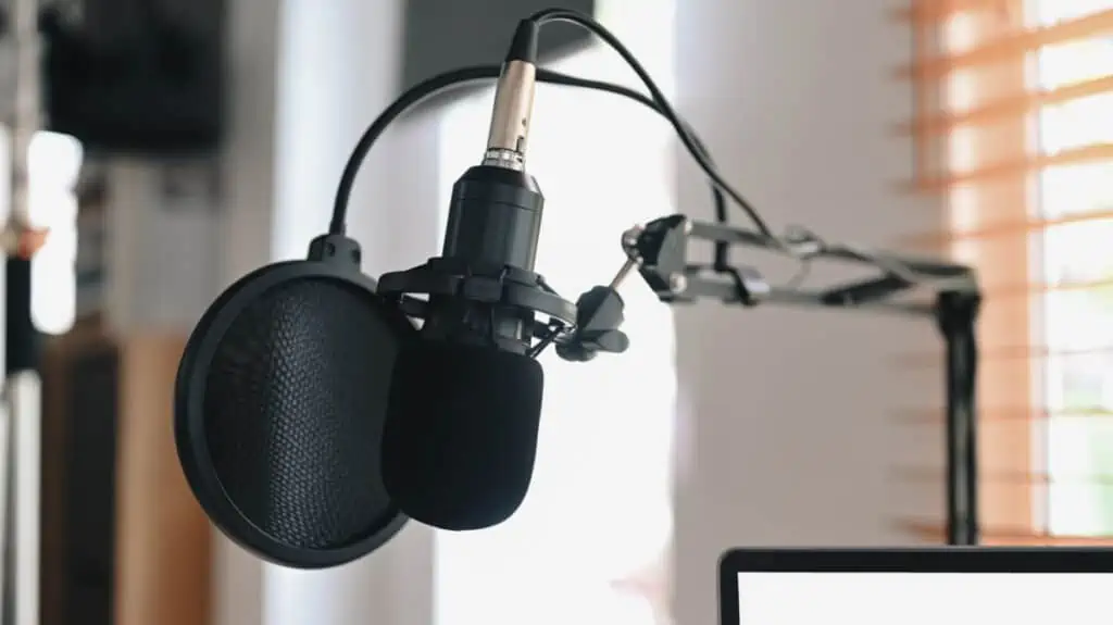 A microphone is sitting on a desk next to a laptop.