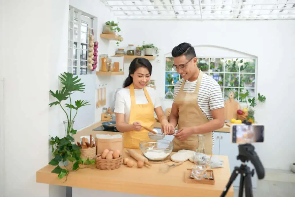 Young asian couple cooking together and recording live video for vlog and social media with professional camera