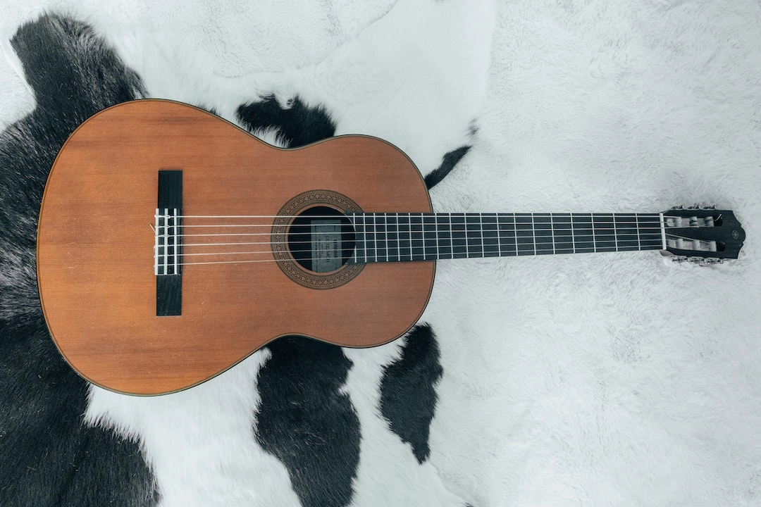 An acoustic guitar laying on a cowhide rug.