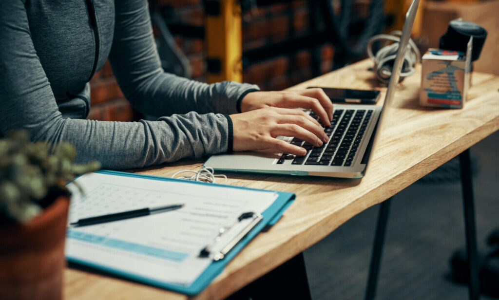 A woman typing on a laptop at a desk.