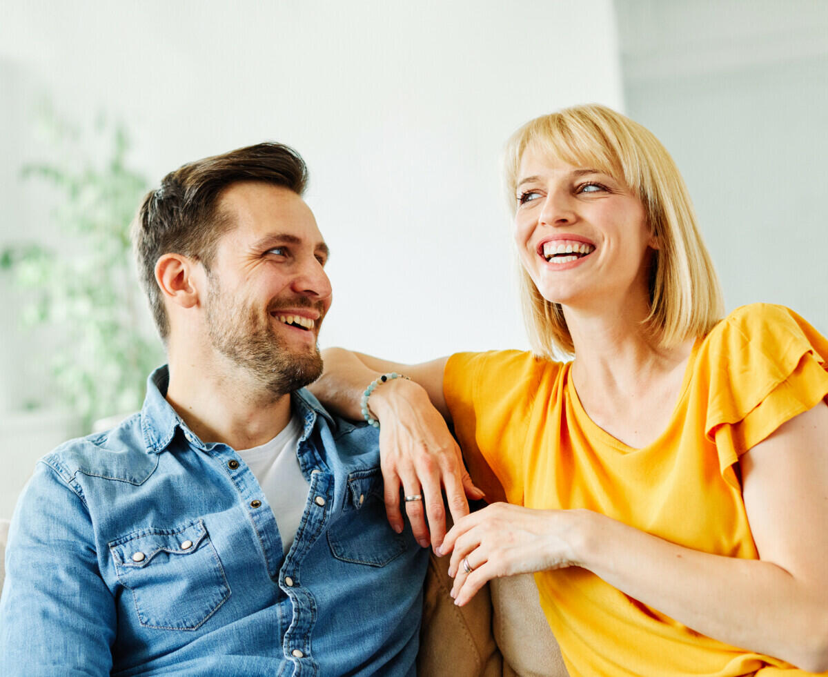 A man and woman sitting on a couch laughing.