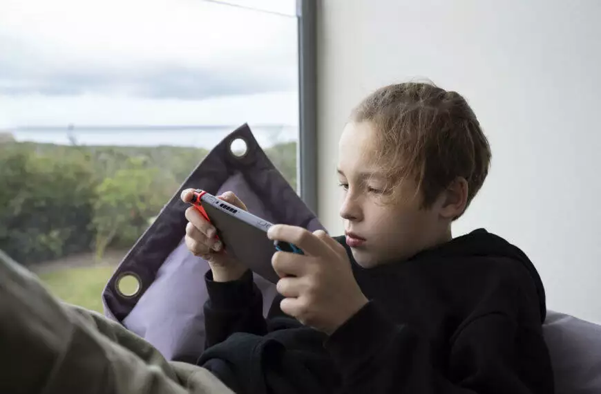 Boy teenager being attracted with game on handheld console
