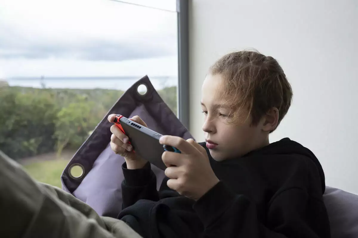 Boy teenager being attracted with game on handheld console