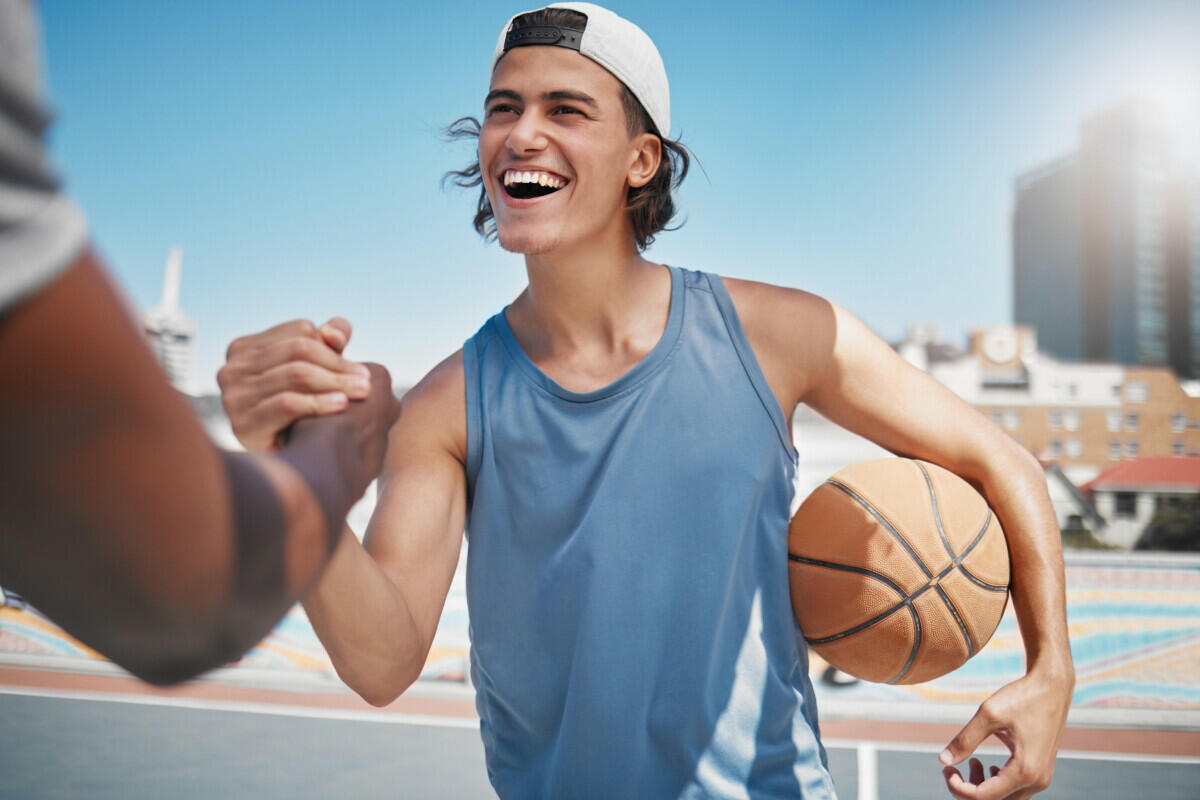 A young man is holding a basketball with another man.