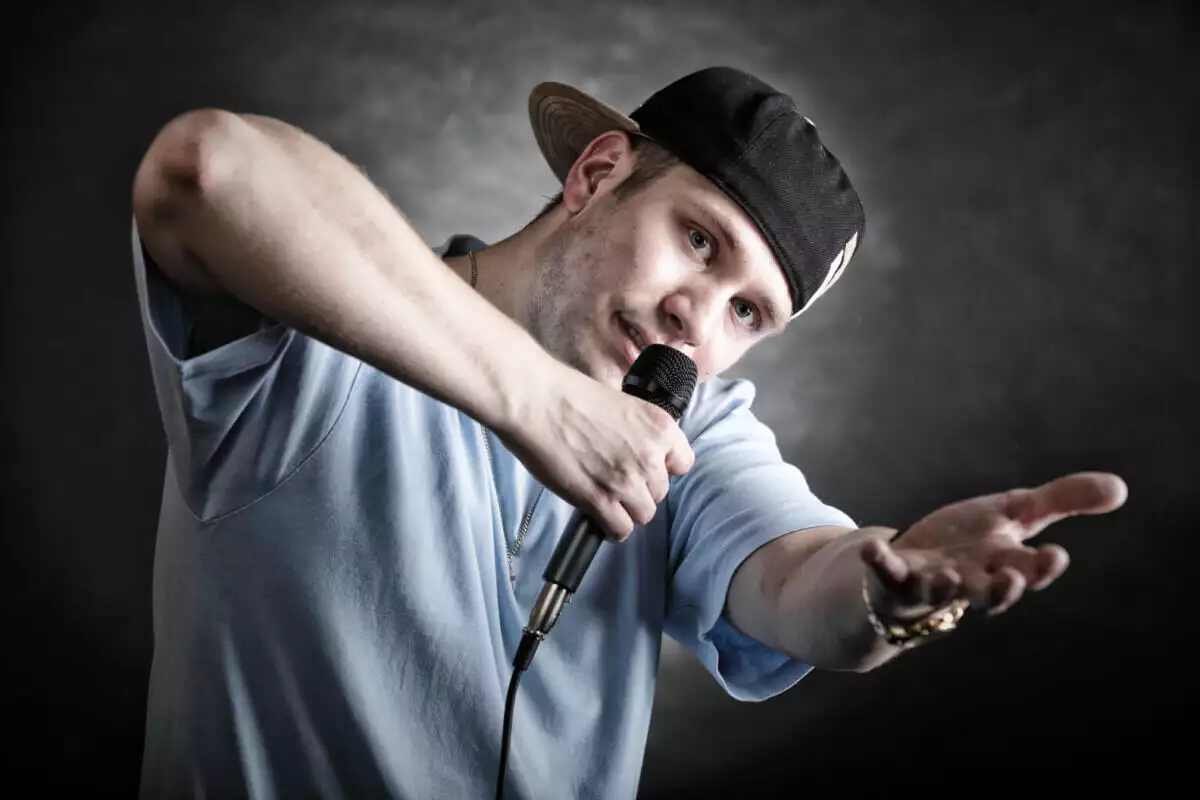 A man in a cap is holding a microphone.