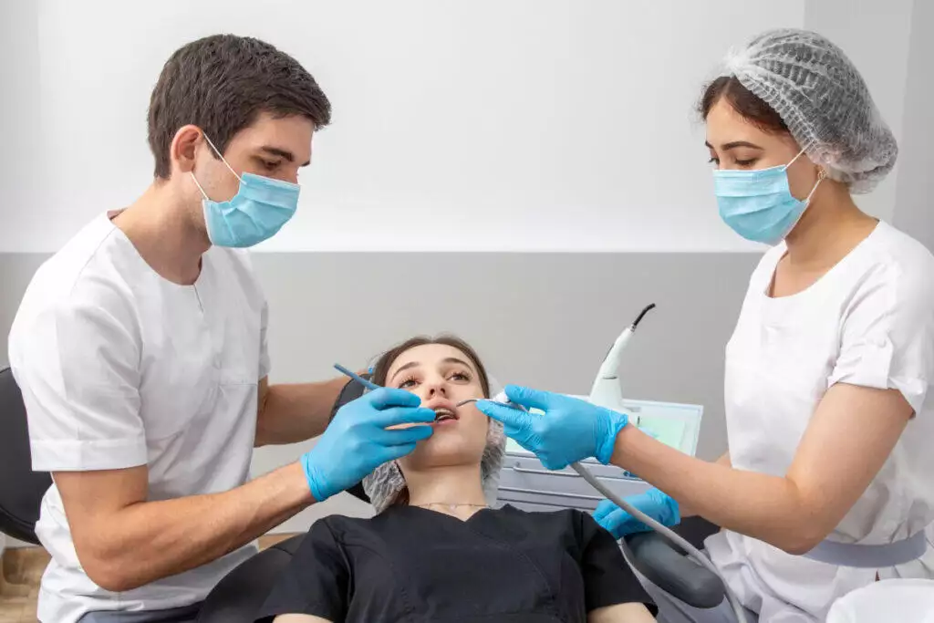 Two dentists are working on a patient's teeth.